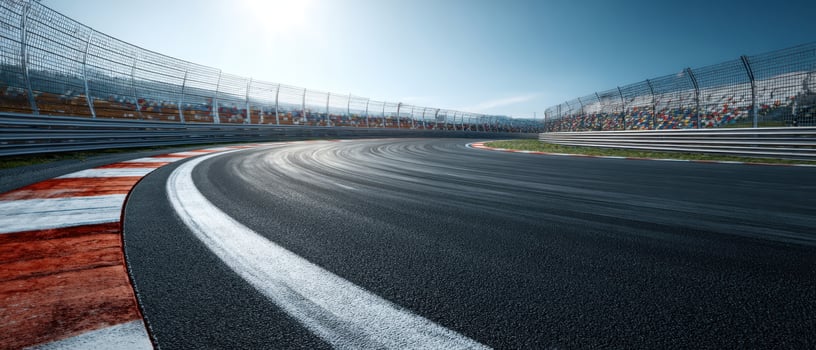 The winding racetrack under a bright blue sky with distant grandstands. photo