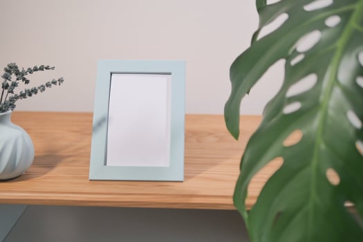Decorative frame on a wooden shelf with greenery nearby photo