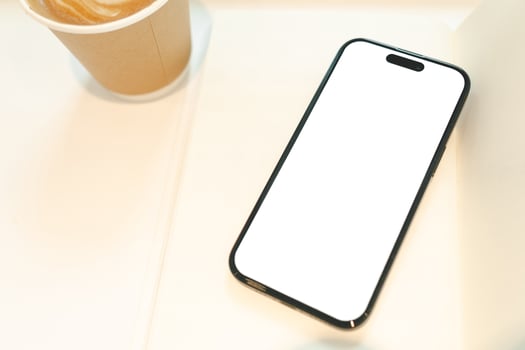 Hand Holding Smartphone with Blank Screen and Coffee Cup. a blank white screen, ideal for app or website mockup. technology, lifestyle, coffee culture, Copy space. photo