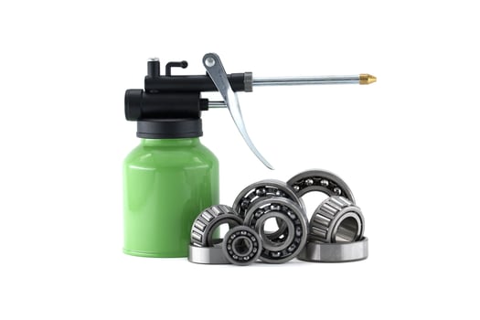 Detailed shot of various bearings with a green oil can, isolated on white. photo
