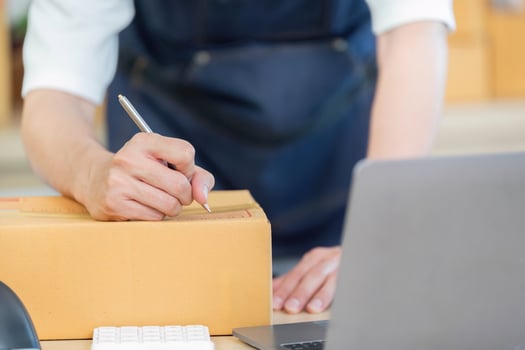 E-commerce. Employee writing on package in shipping department. photo
