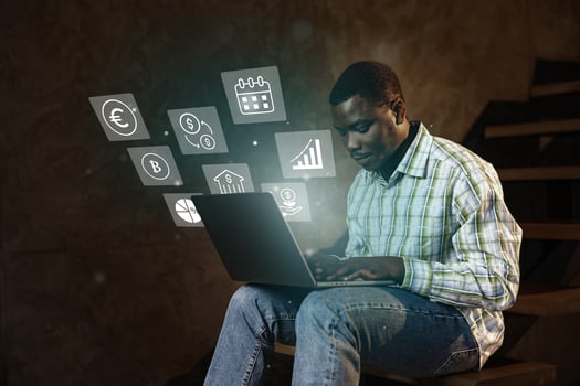 Man working on laptop with digital financial icons illuminated in a cozy indoor setting during evening hours photo