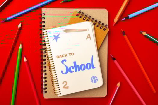 Colorful school supplies arranged on a bright red background, showcasing notebooks and colored pencils ready for new academic year photo