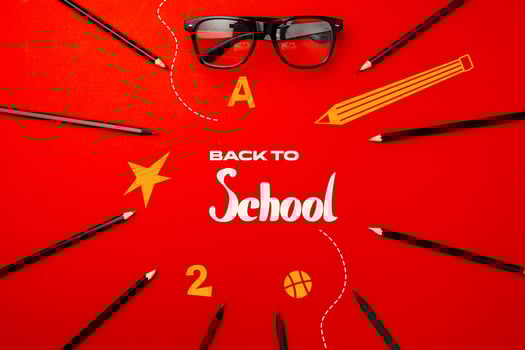 Back to school preparation with creative supplies and stylish glasses on a vibrant red background photo