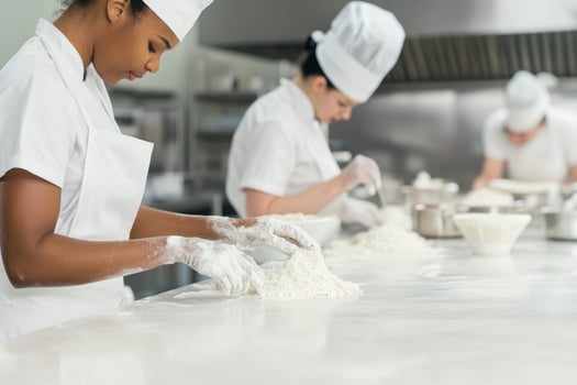 Diverse group of mixers collaborating in a commercial kitchen to prepare culinary ingredients photo