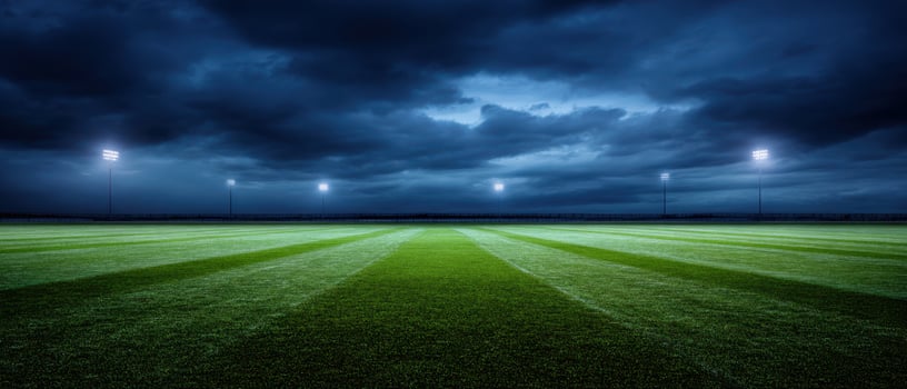 The serene soccer field under dramatic evening skies illuminated by stadium lights photo