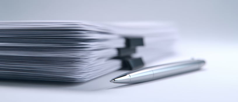 The stack of neatly organized papers beside a sleek silver pen photo