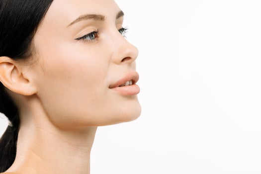 Close-up portrait of a young woman with clear skin and elegant makeup, showcasing her profile against a clean white background, emphasizing beauty and confidence with copy space photo