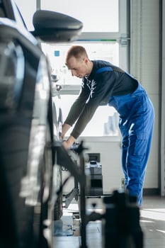 Auto mechanic installing sensor during suspension adjustment and automobile wheel alignment work at repair service station photo