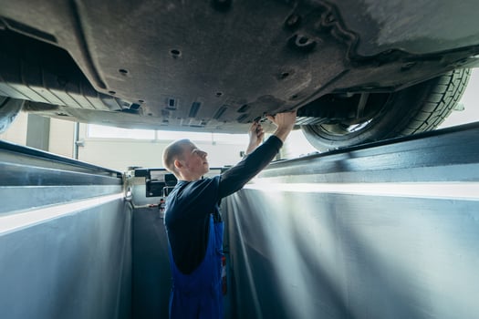 Car mechanic adjusts wheels in a car repair shop photo
