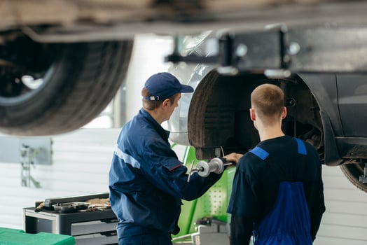 Young car mechanics at repair service station inspecting car wheel and suspension detail photo