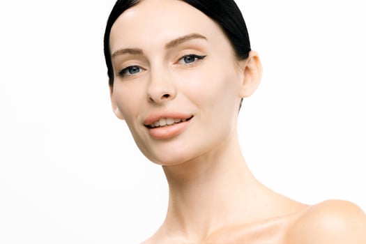 Close-up portrait of a smiling woman with clear skin and minimal makeup, showcasing natural beauty against a bright white background, emphasizing healthy skincare and confidence with copy space photo