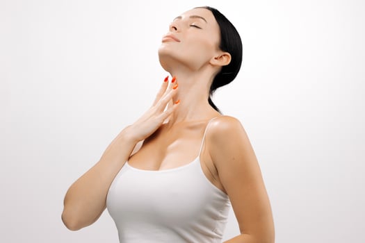 Woman with clear skin gently touching her neck, showcasing healthy complexion and beauty, against a clean white background with soft lighting and serene ambiance photo