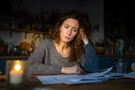 a woman sitting at a table with papers and a candle photo