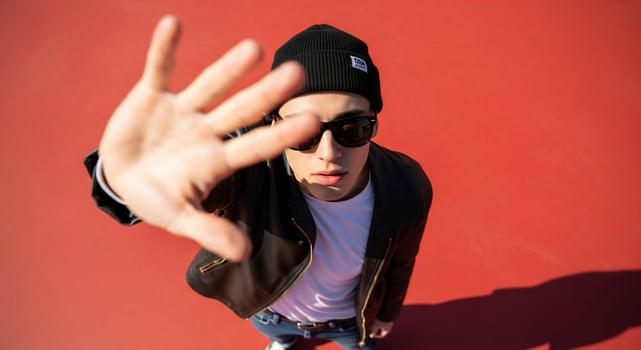 A man in a black hat and sunglasses is making a hand gesture photo