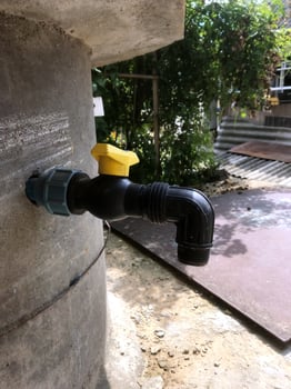 Water tap attached to a concrete structure in a garden area photo