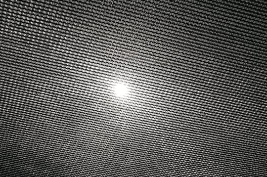 Sun shining through black mesh fabric with bright light photo