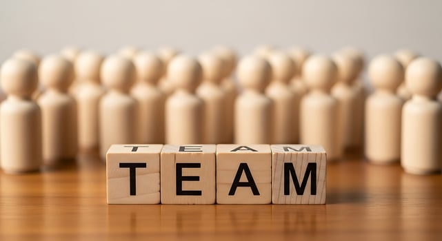 Wooden blocks spell out team with blurred figures behind photo