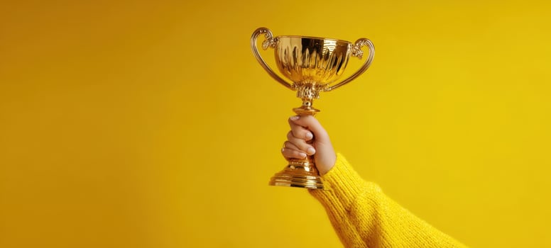 The golden trophy raised in triumph against a vibrant yellow background. photo