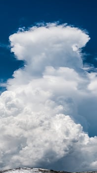 Towering Cumulus Clouds Against a Deep Blue Sky with Snow on Ground. photo