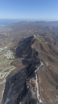 Aerial View of Hillsides Scarred by Wildfire with Residential Areas Nearby. photo
