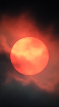 Majestic Red Sun Hidden Behind Dramatic Dark Clouds. photo