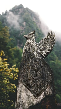 Ancient Carved Wooden Phoenix Statue Overlooking Misty Mountains. photo