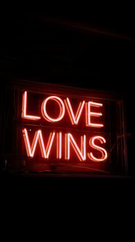 Bright Red Neon Sign That Says Love Wins in the Dark. photo