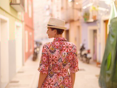 asian Woman in red dress strolls through colorful streets of Spanish coastal town photo