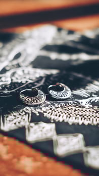 Ornate Silver Earrings Resting on Detailed Fabric. photo