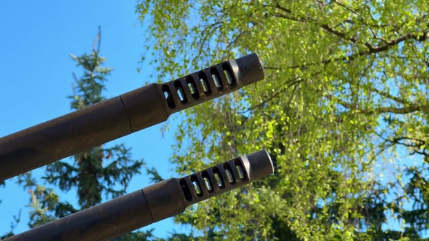 A closeup view of various military weapon barrels set against a clear blue sky backdrop photo