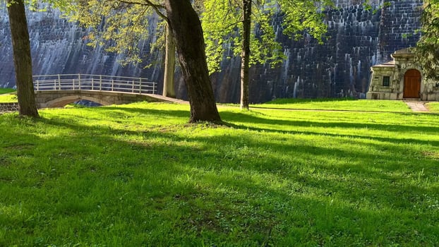 A picturesque and serene park landscape featuring a charming stone pavilion with lush, green grass photo