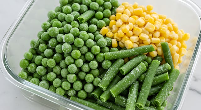 A clear container filled with green peas, corn and green beans photo