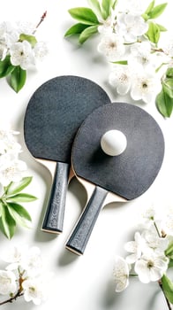 Black Table Tennis Paddles And White Ball Surrounded By Spring Blossoms On White Background For Sporty Lifestyle Visuals, Seasonal Fitness Inspiration, Wellness Trends, And Ping Pong Competition photo