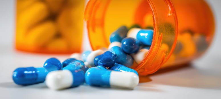 The spilled capsules from an orange prescription bottle on a white surface. photo