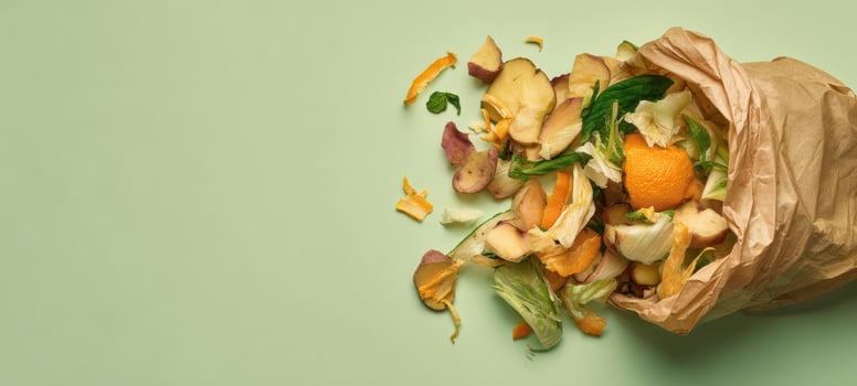 The discarded organic waste spilling from a brown paper bag on green background. photo
