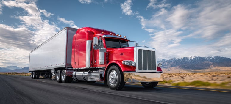The red truck driving along a scenic highway with mountains in the background. photo