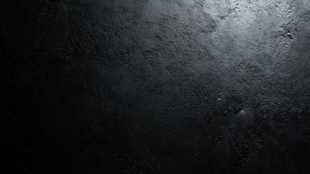 Dark textured surface illuminated by soft light highlights subtle details and depth in the material photo
