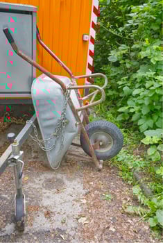 Chained Wheelbarrow by Trailer in Garden photo