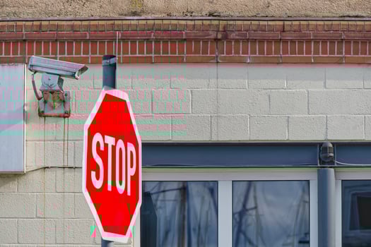 Stop Sign and Security Camera on Building photo