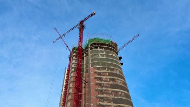 The construction of modern skyscrapers with cranes is taking place under a clear blue sky photo