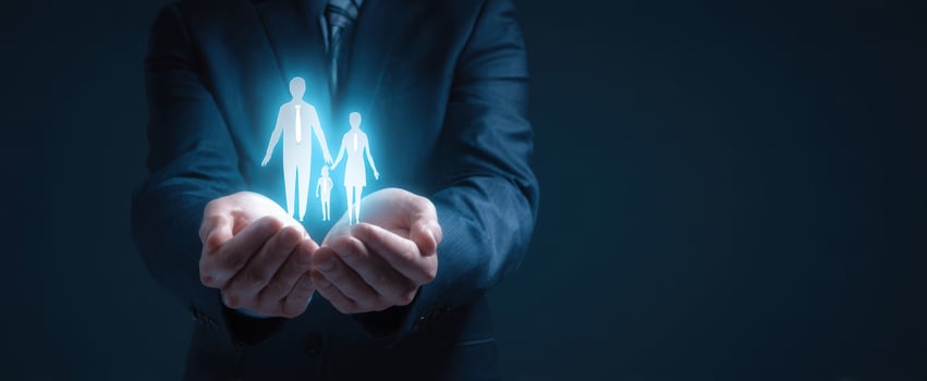 The hands of a businessman holding a glowing family silhouette in a dark setting. photo