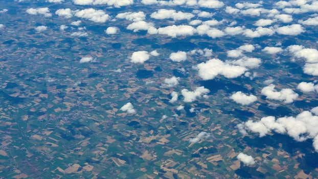 An Aerial View of Lush Green Fields Accompanied by Fluffy White Clouds in the Sky photo