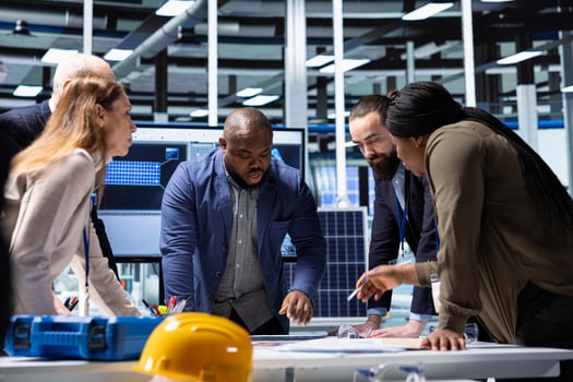 Industrial facility managers and investors analyze technical production data doing brainstorming. Factory management executives discussing manufacturing automation advancements documentation files photo