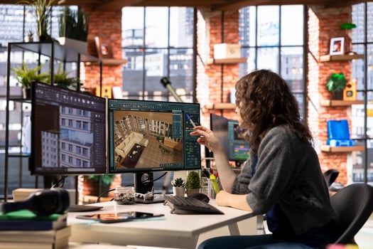 Female arranging virtual assets in a architectural software on dual monitors, creating a detailed 3D render of a floor plan. Woman uses the program for computer aided interior design. photo