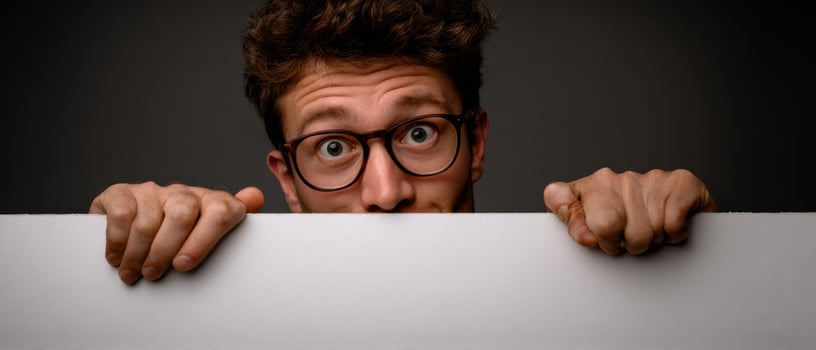 The curious man peeking over a blank sign with a surprised expression. photo