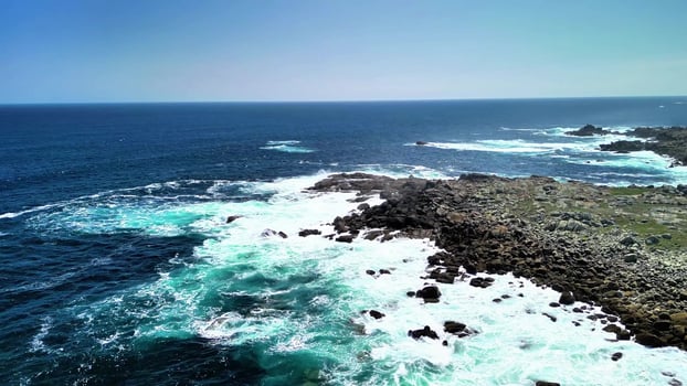 Experience the Stunning Aerial Views Showcasing the Turquoise Ocean and the Rocky Shoreline photo
