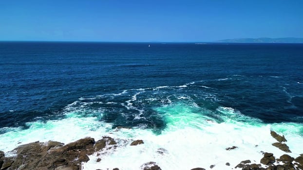 Experience the Stunning Ocean View with Waves Crashing on a Beautiful Rocky Shoreline photo
