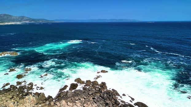 Experience a breathtaking ocean view with a stunning rocky shoreline and vibrant turquoise waves photo
