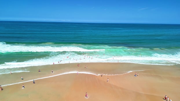 A Beautiful Beach with Clear Blue Waves, Relaxing Sunbathers, and a Scenic Environment photo